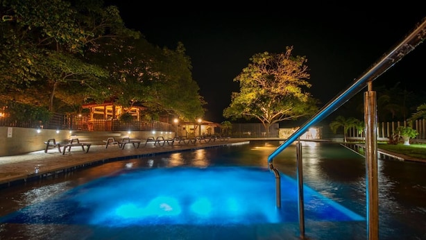 A nighttime pool area with a clear water surface, surrounded by trees and a gazebo. - Samadhi Ecohotel by Rotamundos (Puerto Escondido)