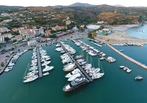 A marina with numerous boats docked, a pier extending into the water, and a town in the background. - Bellavista Central apartment with sea view  (Marina di Camerota SA)