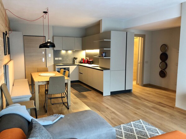 A modern apartment with a dining area, kitchen, and living space.