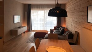 A modern living room with a wooden dining table, a sofa, and a hanging lamp. - 3 bedroom apartment Chalet Bizet (Panice Soprana)