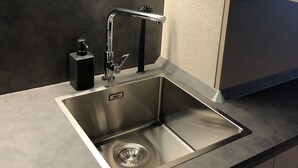 A modern kitchen with a stainless steel sink, a black soap dispenser, and a built-in light above the sink. - 3 bedroom apartment Chalet Bizet (Panice Soprana)
