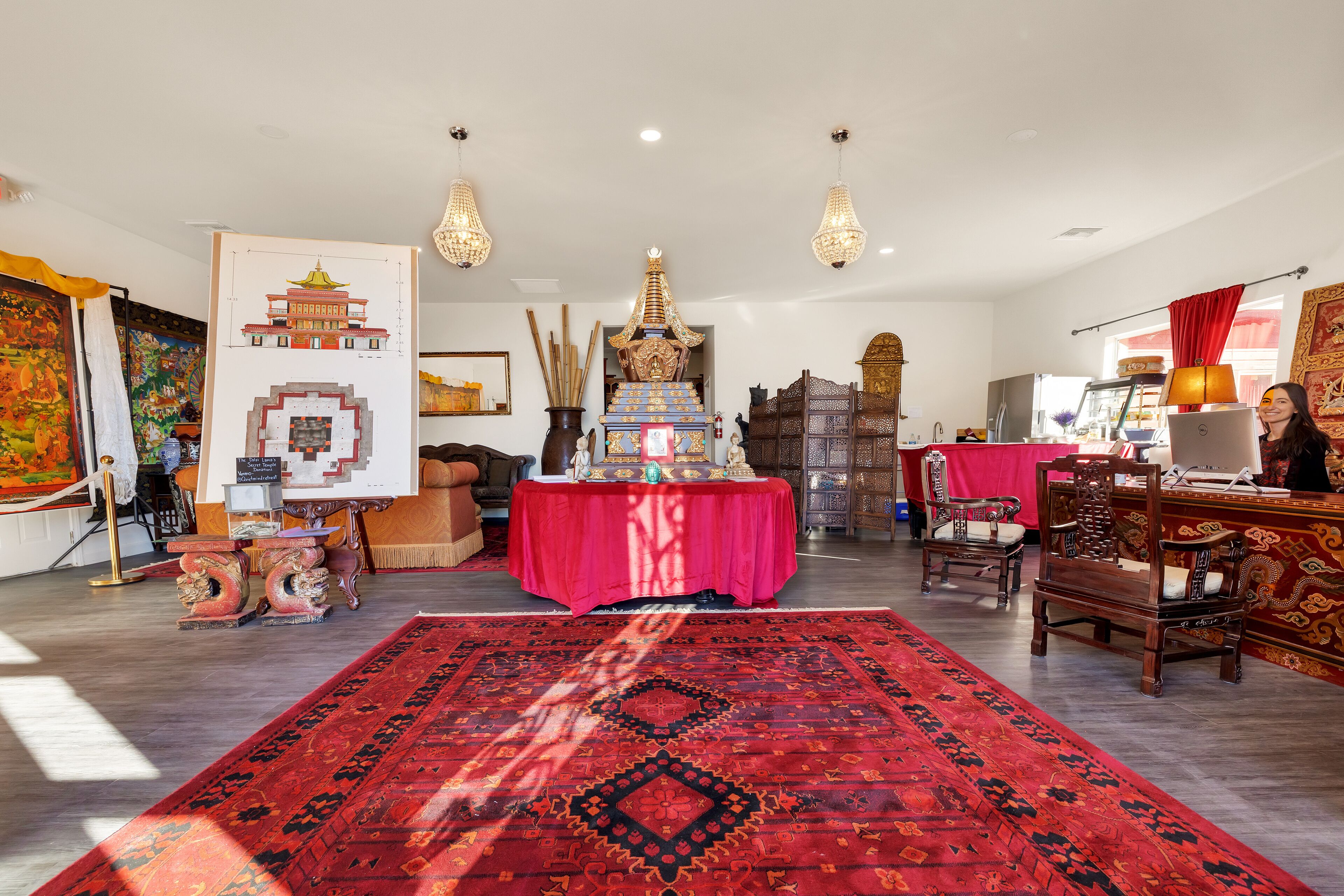 A spacious room with a large red carpet, traditional wooden furniture, and a table with a red cloth.