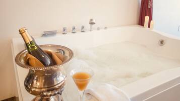 Une salle de bain avec une baignoire, une bouteille de champagne et un verre de champagne.