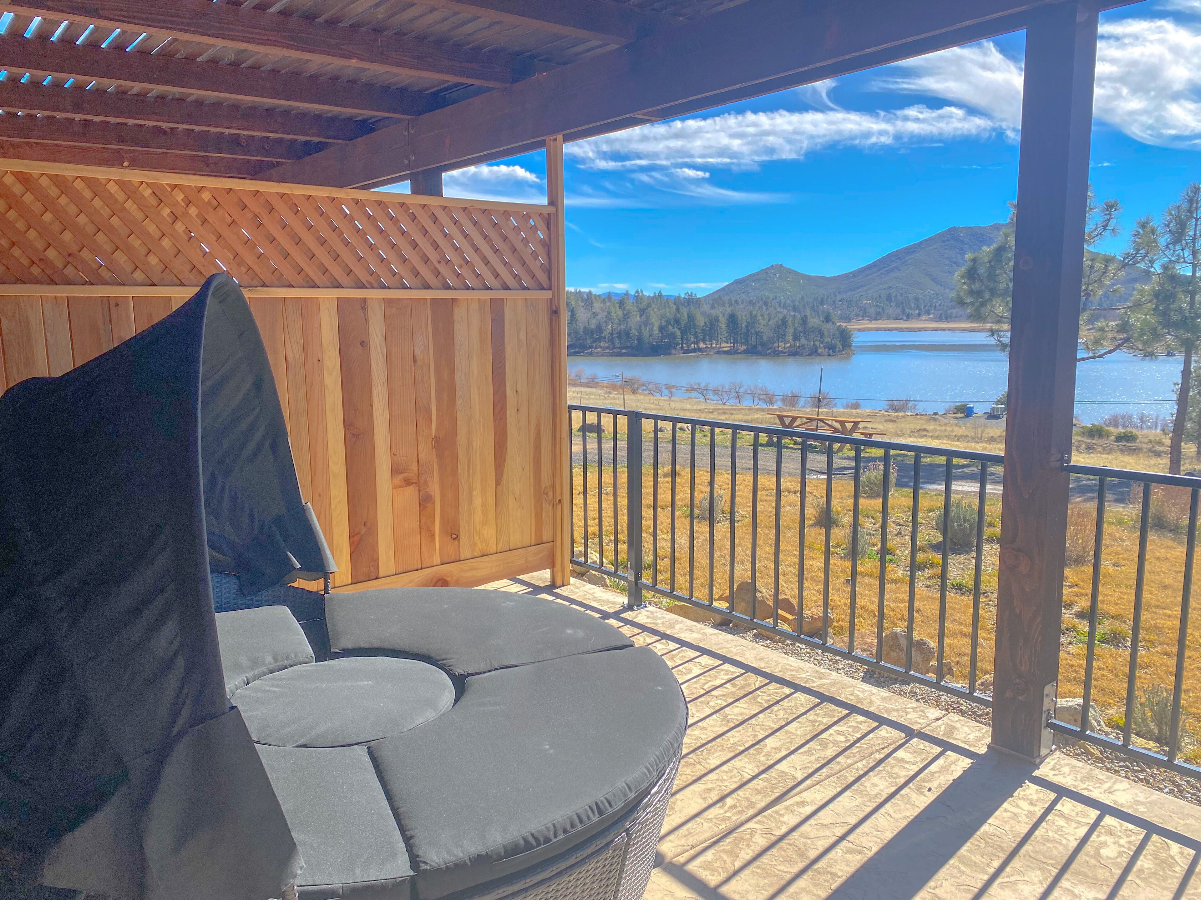 A covered outdoor seating area with a view of a lake and mountains.