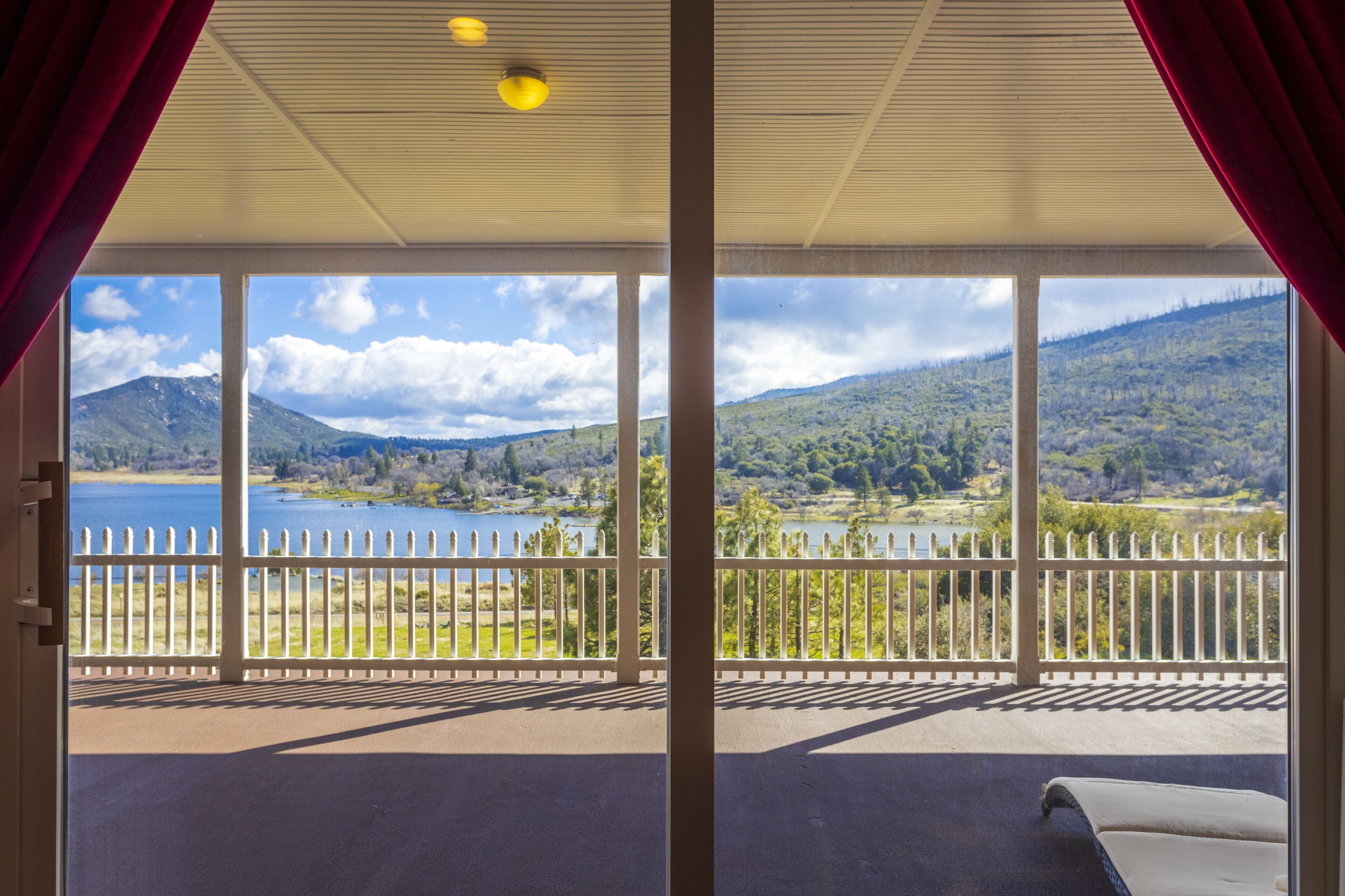 Un balcon avec vue sur un lac, des montagnes et une clôture blanche.