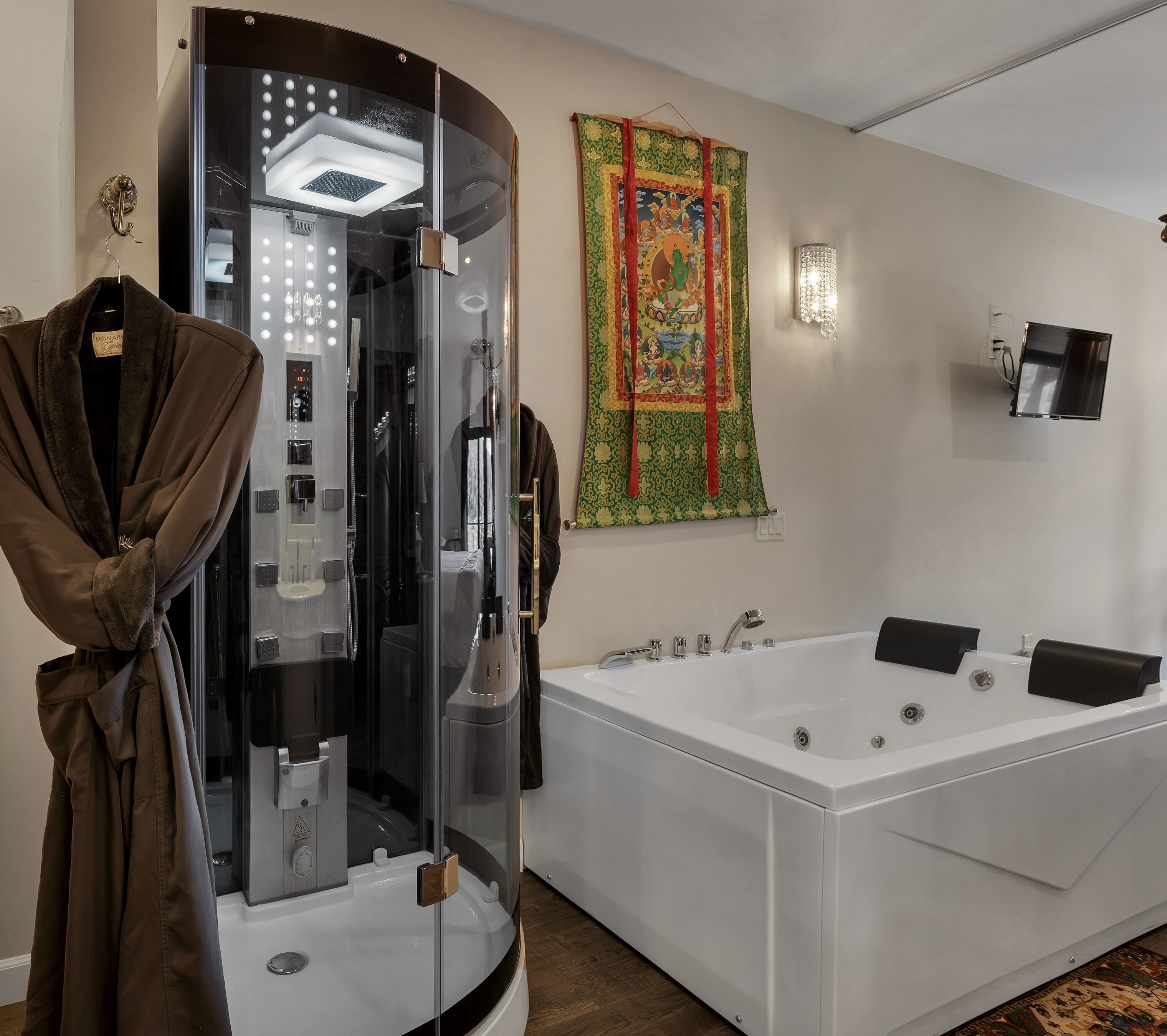 A modern bathroom with a large white bathtub, a glass-enclosed shower, and a decorative tapestry on the wall.