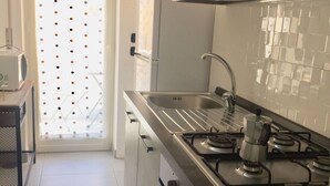Una cocina con electrodomésticos de acero inoxidable, un fregadero y un ventanal con diseño texturizado.