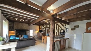 Ein geräumiger Wohnbereich mit Kamin, eine Küche mit Bar und ein Essbereich mit blauen Stühlen.