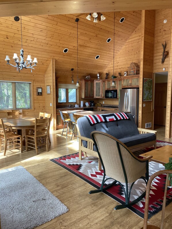 A spacious wooden cabin with a dining area, a sofa with a patterned throw, and a kitchen with modern appliances. - Eagle Pines: Rare, Beautiful North Shore of Gull Lake (Nisswa)