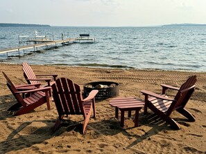 A beach with wooden chairs and a fire pit. - Eagle Pines: Rare, Beautiful North Shore of Gull Lake (Nisswa)