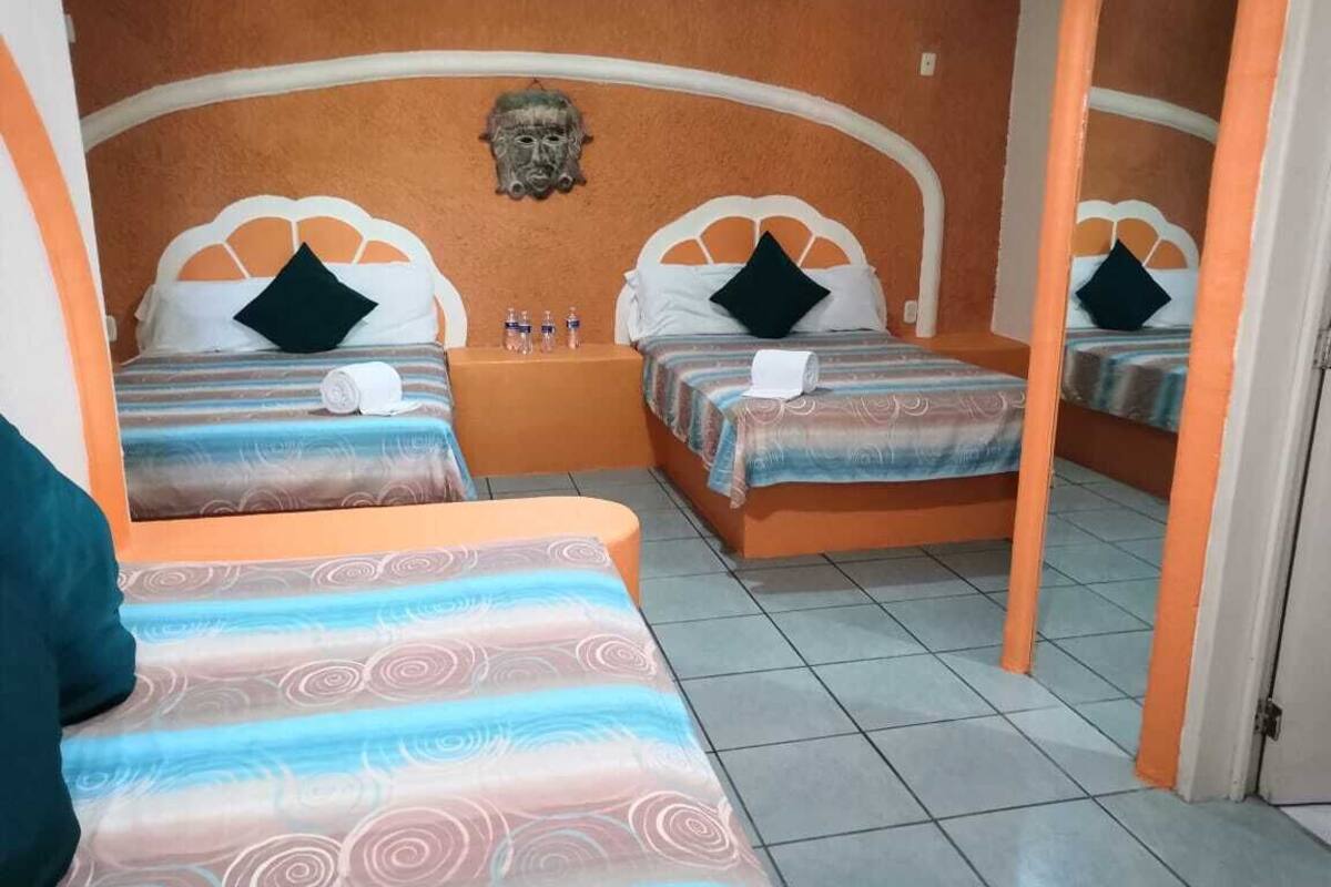 A hotel room with two beds, each with a headboard, pillows, and a rolled towel.