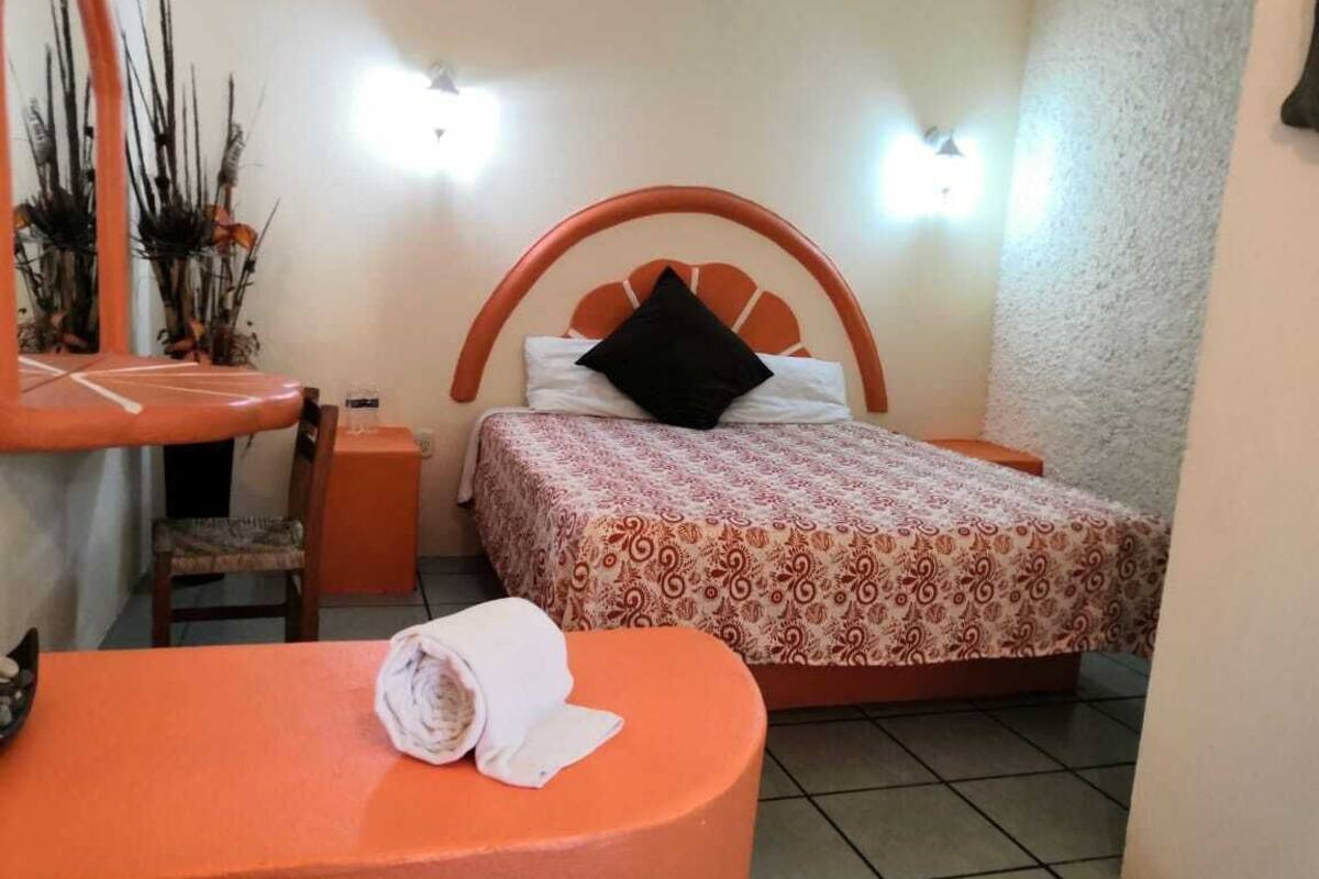 A bedroom with a bed, a small table with a towel, a chair, and a nightstand.