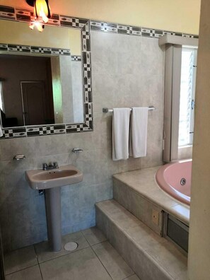 Un baño con lavamanos, espejo y bañera.