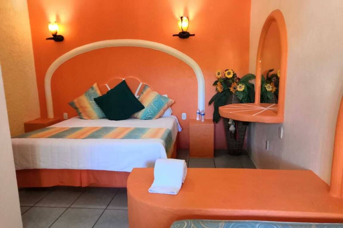 A bedroom with two beds, a small sitting area, and a bathroom with a shower and sink.