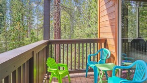 Une terrasse en bois avec une rambarde, entourée d’arbres.