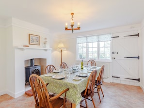 A dining room with a fireplace, a chandelier, and a large window. - 4 bedroom accommodation in Tillingham, near Southminster (Tillingham, near Southminster)