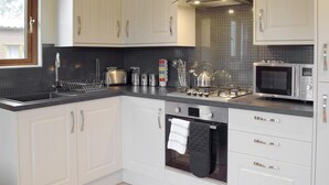 Una cocina moderna con armarios blancos, extractor de acero inoxidable, microondas y horno empotrado.