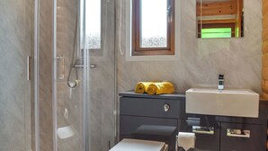 Un baño moderno con ducha de vidrio, tocador con espejo y inodoro.