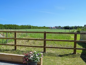 A wooden fence, a grassy field, and a row of houses in the distance.