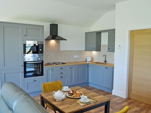 A modern kitchen with grey cabinets, a built-in oven, a gas stove, and a sink.