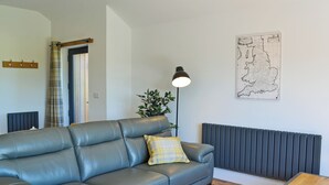 Un soggiorno moderno con un divano grigio, un cuscino giallo, una lampada da terra, una mappa appesa al muro e un termosifone.