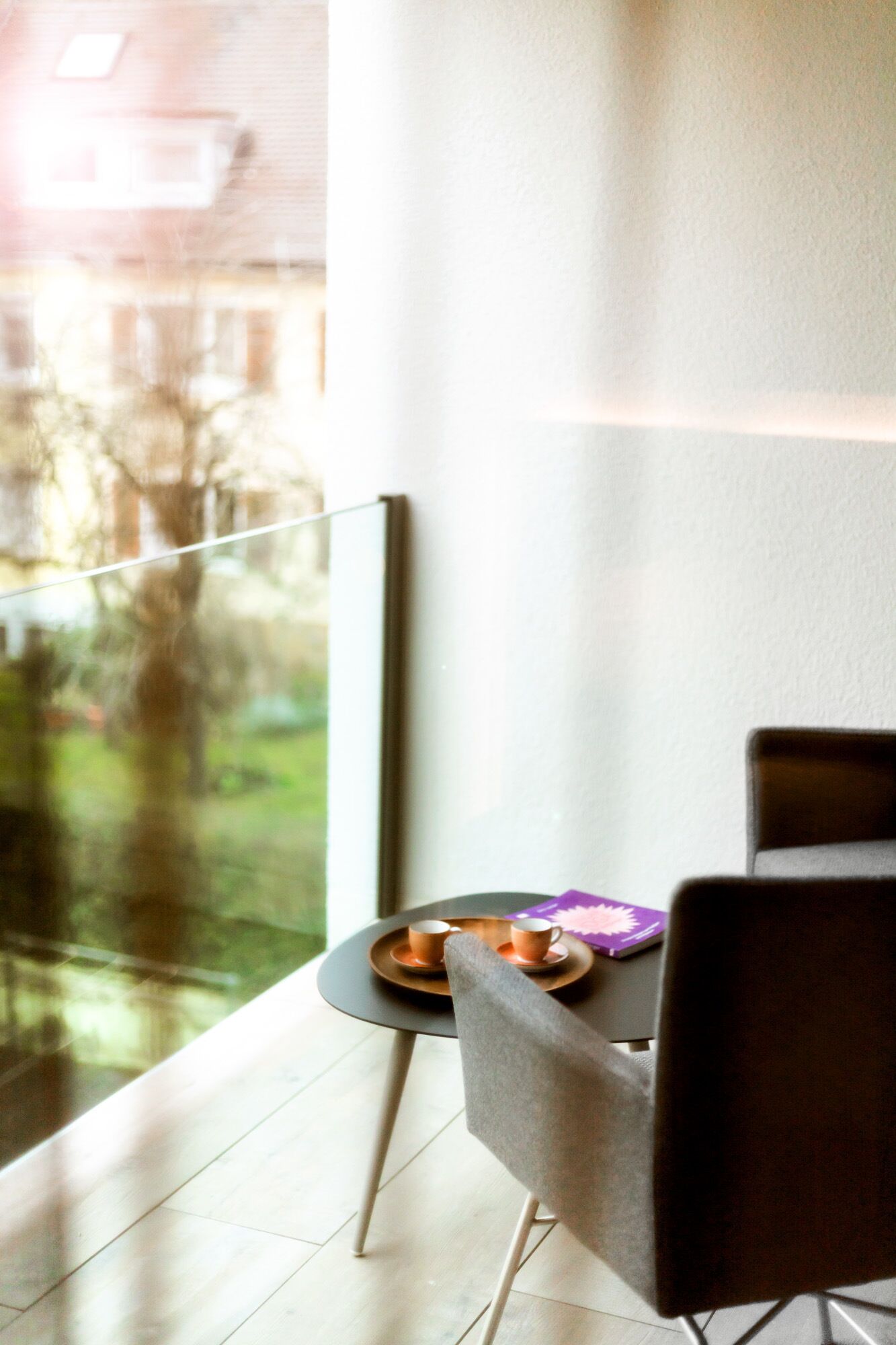 A modern room with a large window, a small table with two cups, and a chair.