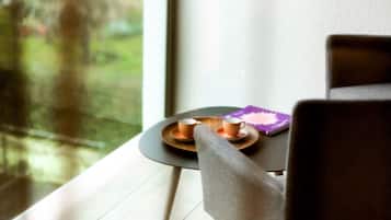 A modern room with a large window, a small table with two cups, and a chair.