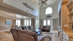 A spacious living room with a large sectional sofa, a coffee table, and a fireplace. There is a dining area with a kitchen counter and cabinets. - Ocean & inlet view home w/Elevator & Private Pool! 2nd Row - 6BR, 6.5BA (Garden City Beach)