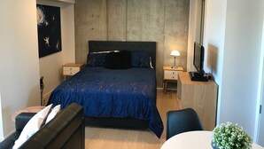 Un dormitorio con una cama grande, dos mesitas de noche, un televisor, un escritorio y una silla.