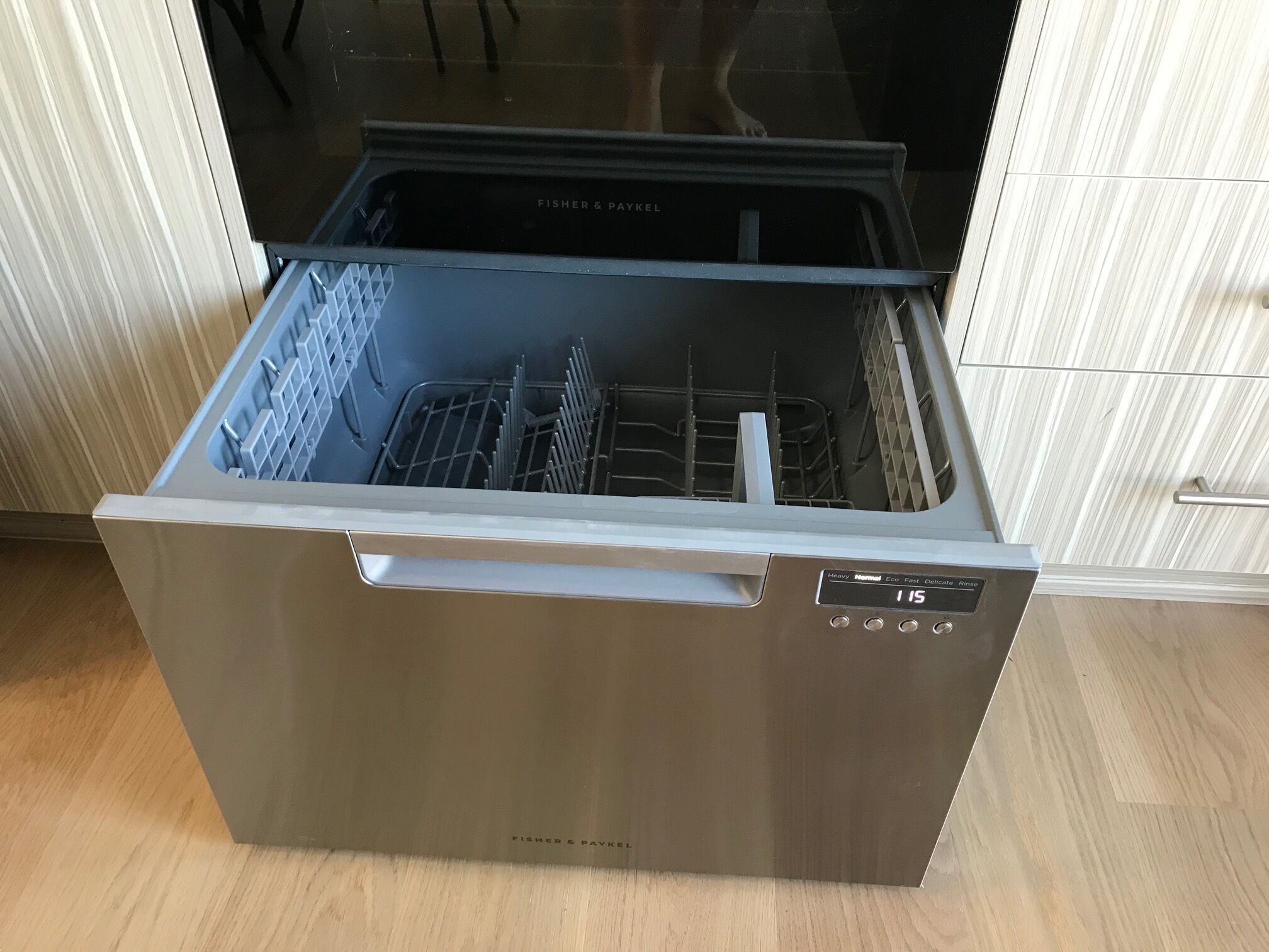 Un lavavajillas abierto con acabado de acero inoxidable, un panel de control con ajustes y una puerta transparente.
