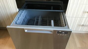 Un lavavajillas abierto con acabado de acero inoxidable, un panel de control con ajustes y una puerta transparente.