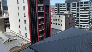 Un edificio moderno con varios pisos, ventanas amplias y un elemento vertical rojo destacado.