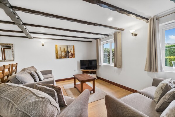 A living room with a sofa set, a wooden coffee table, a TV, and a painting on the wall. - Conveniently located to explore all that Cornwall and Devon have to offer (Notter Bridge)