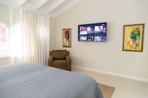 A hotel room with a bed, a recliner, a flat-screen TV mounted on the wall, and two framed artworks. - 2 Bedroom Townhouse at Surbiton Square (Kingston)