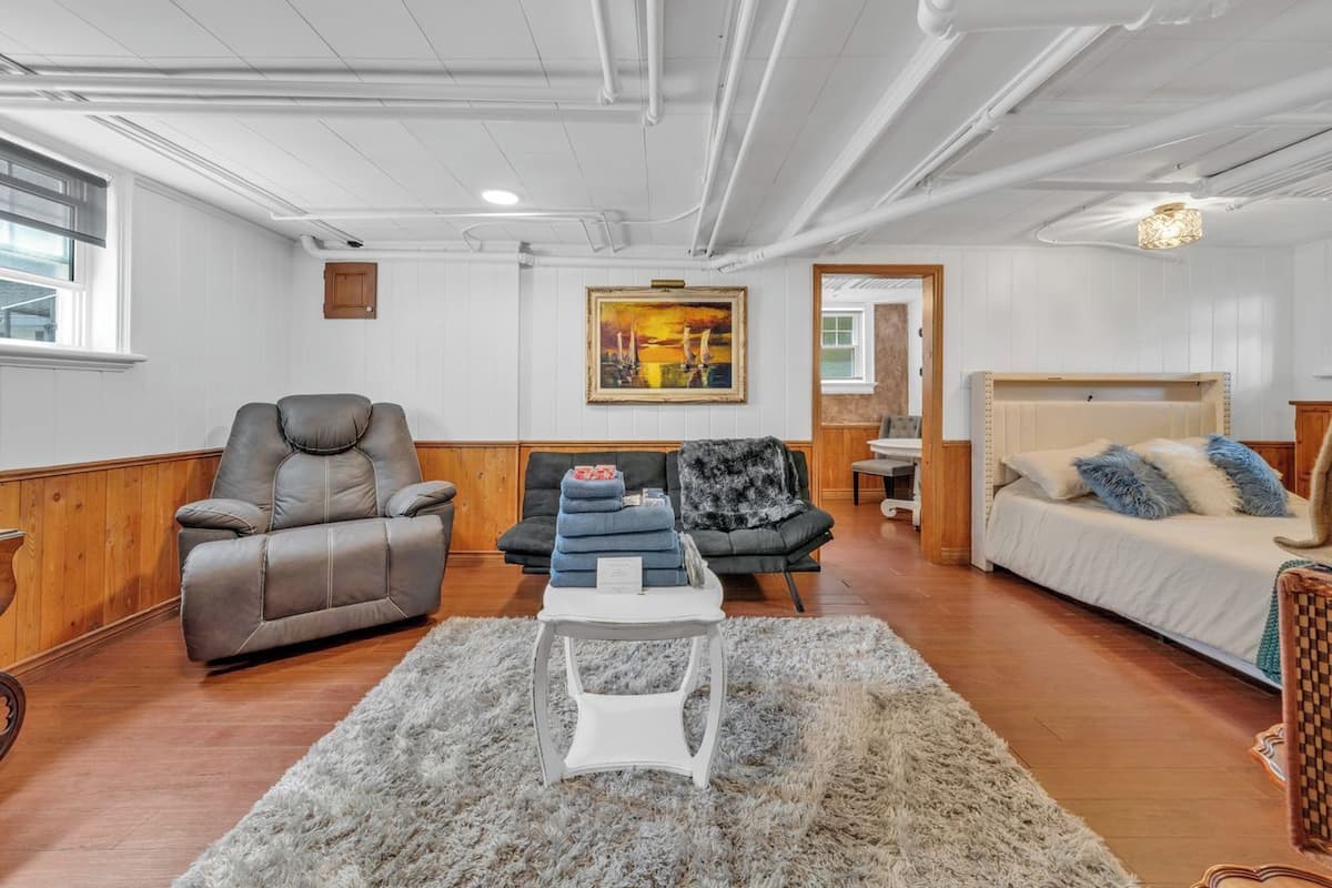A spacious living room with a reclining chair, a sofa, a bed, and a small table.