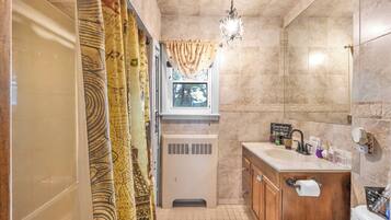 Ein kleines Badezimmer mit Dusche, Fenster, Waschbecken und Toilette.