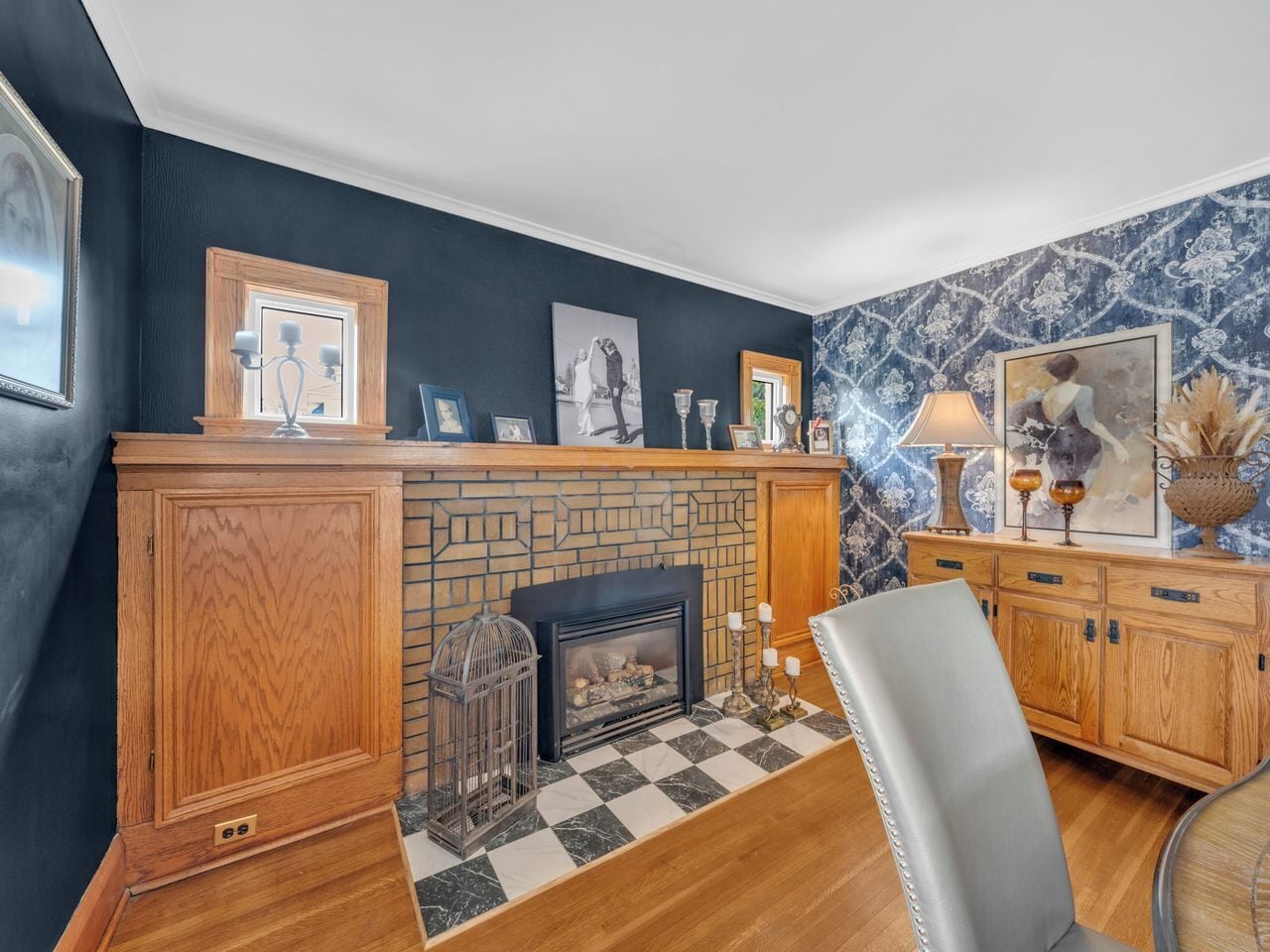 A room with a fireplace, wooden cabinets, and a checkered floor.