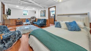 A spacious room with a large bed, a sofa, a chair, and a small table. - Nicklin House (Leamington)