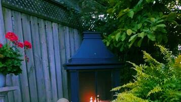 A wooden fence with a blue chimney, a potted plant with red flowers, and green foliage.