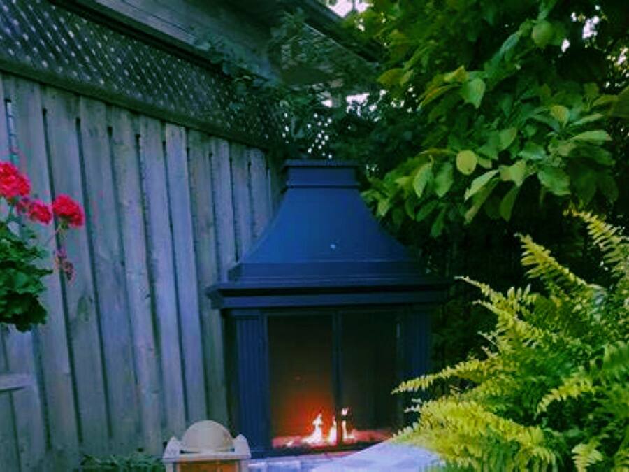 A wooden fence with a blue chimney, a potted plant with red flowers, and green foliage.