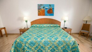 Een slaapkamer met een groot bed, twee nachtkastjes, een stoel en een schilderij aan de muur.