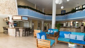 Een ruime lobby met een bar, zithoekjes en een hoge plafond met decoratieve verlichting.