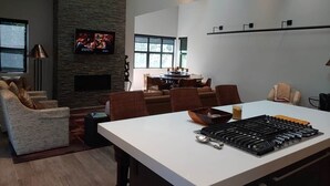 Una sala de estar moderna con chimenea, comedor y isla de cocina.