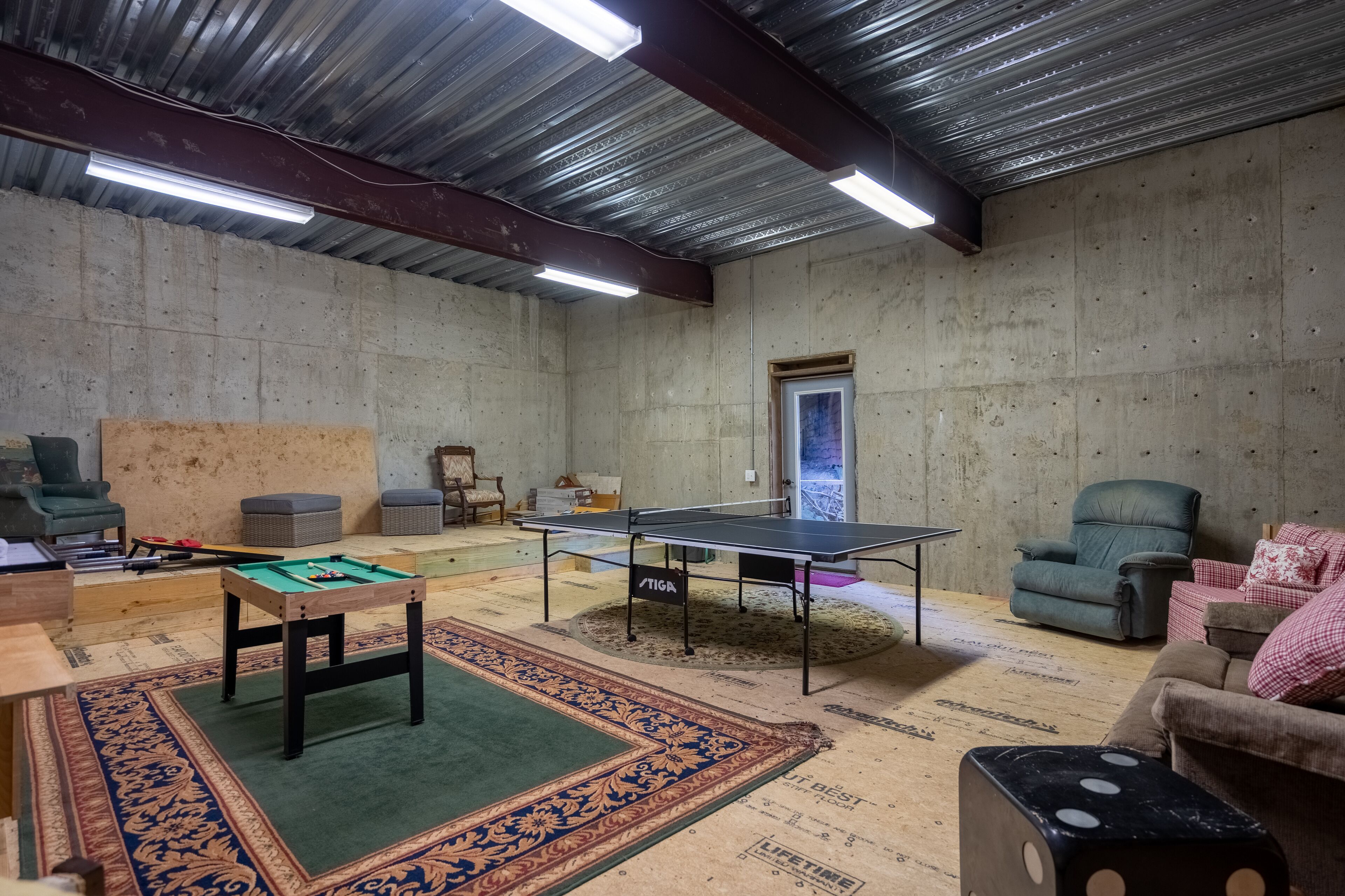 A room with a ping pong table, pool table, and comfortable seating.