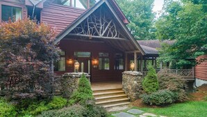 A log cabin with a stone entrance, a porch, and a well-maintained garden.