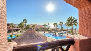 Vista de un resort con piscina, palmeras y cielo despejado.