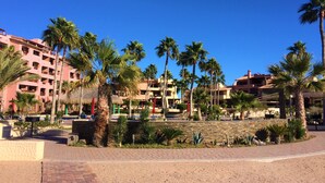 Un resort con edificios de varios pisos, palmeras y un patio empedrado.