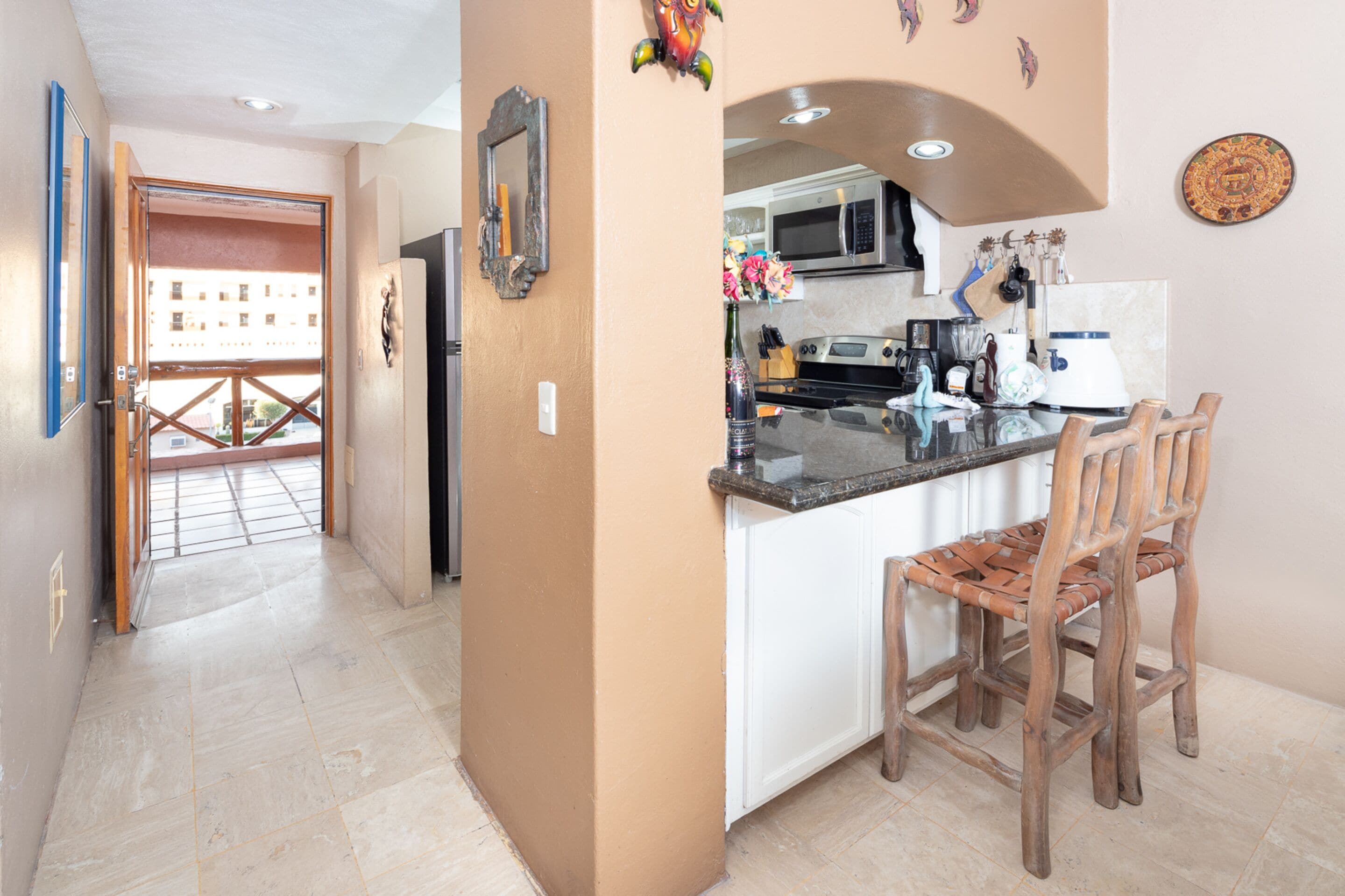 Una cocina con una isla central, sillas de madera y vistas al exterior.