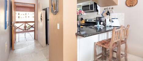 Una cocina con una isla central, sillas de madera y vistas al exterior.