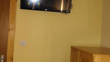 A room with a mounted flat-screen TV, a wooden cabinet, and a radiator.